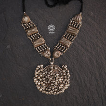 This Tribal Silver Neckpiece features a stunning vintage Ghungroo pendant and delicate silver bands. A perfect accessory for celebrating Navratri, this necklace adds a touch of traditional elegance to any outfit. Embrace cultural heritage with this unique piece.