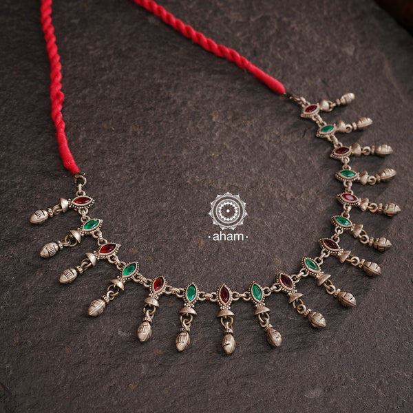 Expertly crafted, this Silver Neckpiece offers versatility in its design. With the ability to be worn as both a short neckpiece and a choker, this beautiful piece is adorned with green and red stone highlights, adding a touch of fun to any outfit. Perfect for any occasion.