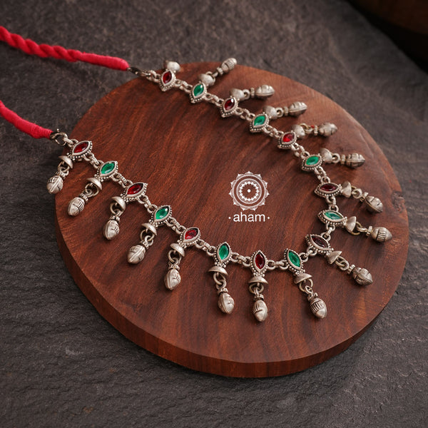 Expertly crafted, this Silver Neckpiece offers versatility in its design. With the ability to be worn as both a short neckpiece and a choker, this beautiful piece is adorned with green and red stone highlights, adding a touch of fun to any outfit. Perfect for any occasion.