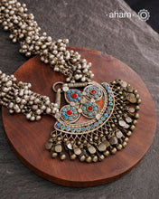 This Tribal Silver Neckpiece features a stunning pendant that was originally a headpiece complemented by tribal chains with multiple ghungroos for added drama. A true treasure for any jewellery lover.