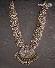 This Tribal Silver Neckpiece features a stunning pendant that was originally a headpiece complemented by tribal chains with multiple ghungroos for added drama. A true treasure for any jewellery lover.