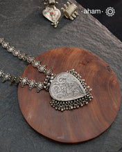 This Tribal Silver Neckpiece features a heart-shaped pendant adorned with intricately crafted peacocks at the top, symbolizing grace and beauty. Multiple small ghungroos hang delicately from the pendant, adding subtle movement and traditional charm. The side bands are embellished with finely detailed floral motifs, enhancing the piece’s artisanal appeal. Crafted entirely in silver, this neckpiece combines cultural symbolism with expert craftsmanship, making it a distinctive accessory for those who appreciat
