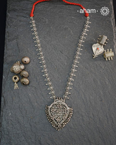 This Tribal Silver Neckpiece features a heart-shaped pendant adorned with intricately crafted peacocks at the top, symbolizing grace and beauty. Multiple small ghungroos hang delicately from the pendant, adding subtle movement and traditional charm. The side bands are embellished with finely detailed floral motifs, enhancing the piece’s artisanal appeal. Crafted entirely in silver, this neckpiece combines cultural symbolism with expert craftsmanship, making it a distinctive accessory for those who appreciat
