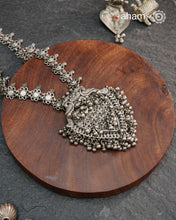 This Tribal Silver Neckpiece features a heart-shaped pendant adorned with intricately crafted peacocks at the top, symbolizing grace and beauty. Multiple small ghungroos hang delicately from the pendant, adding subtle movement and traditional charm. The side bands are embellished with finely detailed floral motifs, enhancing the piece’s artisanal appeal. Crafted entirely in silver, this neckpiece combines cultural symbolism with expert craftsmanship, making it a distinctive accessory for those who appreciat