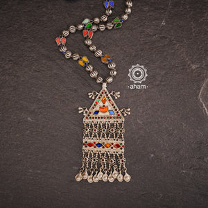 Experience the elegance and timelessness of our Tribal Silver Neckpiece. Handcrafted with a vintage silver piece, highlighted with vibrant coloured glass, and adorned with  silver beads, this necklace is a true statement of style. Complement any outfit with its unique and intricate design.