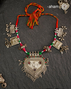 Crafted in stunning silver, this Tribal Silver Neckpiece is a one of a kind accessory that showcases a beautiful combination of vintage pieces threaded together. Its unique design is perfect for Navratri celebrations, making it a must-have addition to your jewellery collection. Elevate any outfit with its elegant, statement-making style.