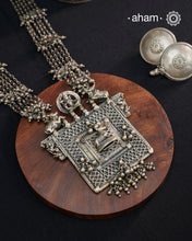 This expertly crafted silver neckpiece features a square amulet intricately depicting Lord Shiva alongside Nandi, embodying traditional tribal artistry. The side chains adorned with numerous ghungroos add a rhythmic charm, enhancing its cultural authenticity. Perfect for those who appreciate heritage craftsmanship and spiritual symbolism in their jewelry collection.
