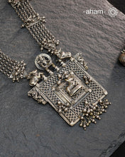 This expertly crafted silver neckpiece features a square amulet intricately depicting Lord Shiva alongside Nandi, embodying traditional tribal artistry. The side chains adorned with numerous ghungroos add a rhythmic charm, enhancing its cultural authenticity. Perfect for those who appreciate heritage craftsmanship and spiritual symbolism in their jewelry collection.