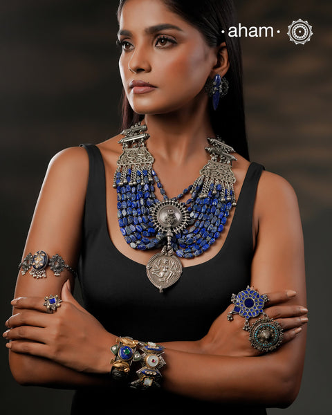 This Tribal Silver Neckpiece is a unique masterpiece designed to make a bold statement. Crafted from vintage silver pieces, it features lapiz stones. Its versatile design complements both traditional and western outfits, offering a distinctive touch to your style. Perfect for those who appreciate unique statement pieces. 