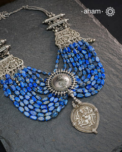 This Tribal Silver Neckpiece is a unique masterpiece designed to make a bold statement. Crafted from vintage silver pieces, it features lapiz stones. Its versatile design complements both traditional and western outfits, offering a distinctive touch to your style. Perfect for those who appreciate unique statement pieces.