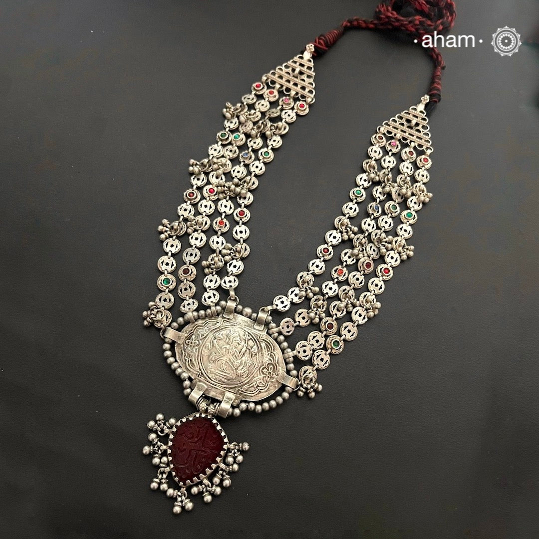 This tribal silver neckpiece is an expertly crafted statement piece, featuring a vibrant red glass drop and four strands on each side. Made from genuine silver, this neckpiece is a unique addition to any wardrobe and is sure to make a bold, stylish statement. Elevate your look with this stunning piece.