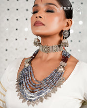 This Tribal Silver Neckpiece is a unique masterpiece designed to make a bold statement. Crafted from vintage silver pieces, it features tumbled iolite stones and a vibrant garnet accent at the top. Its versatile design complements both traditional and western outfits, offering a distinctive touch to your style. Perfect for those who appreciate unique statement pieces.&nbsp;