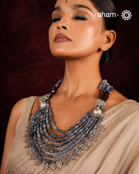 This Tribal Silver Neckpiece is a unique masterpiece designed to make a bold statement. Crafted from vintage silver pieces, it features tumbled iolite stones and a vibrant garnet accent at the top. Its versatile design complements both traditional and western outfits, offering a distinctive touch to your style. Perfect for those who appreciate unique statement pieces.