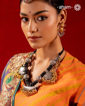 Elevate your style with this Tribal Two Tone Silver Neckpiece, featuring a captivating amulet center framed by elegant paan-shaped beads. The gold-dipped ghungroos add a stunning dual-tone contrast, making this piece truly one-of-a-kind. Perfect for those who want to make a bold cultural statement while embracing exquisite craftsmanship. Don’t miss the chance to own a unique accessory.