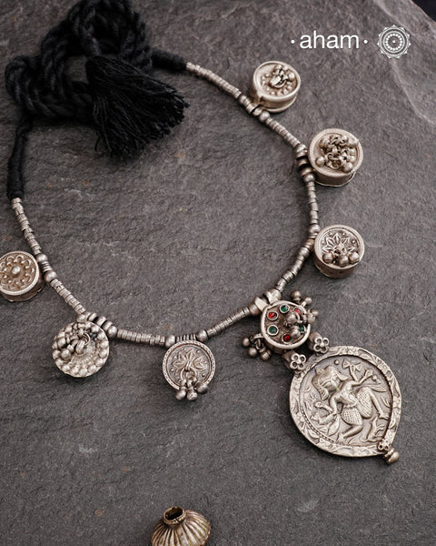 The Tribal Silver Neckpiece is an exceptional piece featuring a meticulously stamped silver pendant of Kal Bhairav. This distinctive design incorporates seven vintage kajal boxes, carefully threaded together with beads to create a harmonious blend of cultural heritage and artisanal craftsmanship. Ideal for connoisseurs of unique jewelry, this neckpiece offers both symbolic depth and aesthetic appeal.