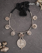 The Tribal Silver Neckpiece is an exceptional piece featuring a meticulously stamped silver pendant of Kal Bhairav. This distinctive design incorporates seven vintage kajal boxes, carefully threaded together with beads to create a harmonious blend of cultural heritage and artisanal craftsmanship. Ideal for connoisseurs of unique jewelry, this neckpiece offers both symbolic depth and aesthetic appeal.