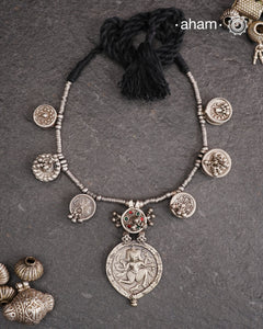 The Tribal Silver Neckpiece is an exceptional piece featuring a meticulously stamped silver pendant of Kal Bhairav. This distinctive design incorporates seven vintage kajal boxes, carefully threaded together with beads to create a harmonious blend of cultural heritage and artisanal craftsmanship. Ideal for connoisseurs of unique jewelry, this neckpiece offers both symbolic depth and aesthetic appeal.