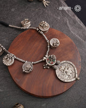 The Tribal Silver Neckpiece is an exceptional piece featuring a meticulously stamped silver pendant of Kal Bhairav. This distinctive design incorporates seven vintage kajal boxes, carefully threaded together with beads to create a harmonious blend of cultural heritage and artisanal craftsmanship. Ideal for connoisseurs of unique jewelry, this neckpiece offers both symbolic depth and aesthetic appeal.