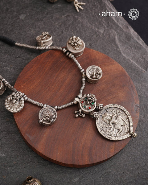 The Tribal Silver Neckpiece is an exceptional piece featuring a meticulously stamped silver pendant of Kal Bhairav. This distinctive design incorporates seven vintage kajal boxes, carefully threaded together with beads to create a harmonious blend of cultural heritage and artisanal craftsmanship. Ideal for connoisseurs of unique jewelry, this neckpiece offers both symbolic depth and aesthetic appeal.
