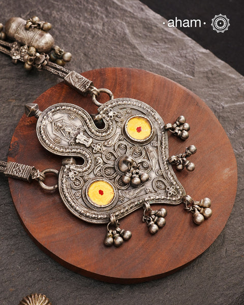 This Tribal Silver Neckpiece from Gujarat embodies the rich heritage of the Rabari community in the Kutch region. Featuring a distinctive arrowhead amulet pendant (chagda) flanked by traditional amulet chains (madaliya), this handcrafted silver piece carries generations of cultural significance. Wearing it connects you to timeless traditions while adding a unique, authentic touch to your style.