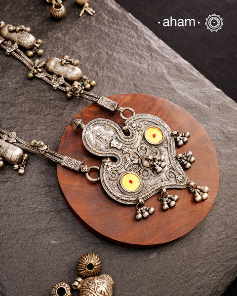 This Tribal Silver Neckpiece from Gujarat embodies the rich heritage of the Rabari community in the Kutch region. Featuring a distinctive arrowhead amulet pendant (chagda) flanked by traditional amulet chains (madaliya), this handcrafted silver piece carries generations of cultural significance. Wearing it connects you to timeless traditions while adding a unique, authentic touch to your style.