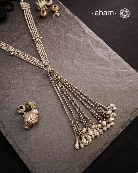 This Vintage Tribal Silver Neckpiece combines two unique tribal designs into one elegant creation. Crafted from silver, it features a simple yet striking long silhouette that enhances any outfit. The standout mango ambi beads at the bottom add a distinctive touch, showcasing expert craftsmanship and timeless style. Perfect for those who appreciate authentic vintage artistry with a refined finish.