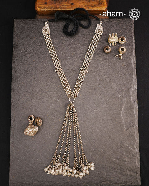 This Vintage Tribal Silver Neckpiece combines two unique tribal designs into one elegant creation. Crafted from silver, it features a simple yet striking long silhouette that enhances any outfit. The standout mango ambi beads at the bottom add a distinctive touch, showcasing expert craftsmanship and timeless style. Perfect for those who appreciate authentic vintage artistry with a refined finish.