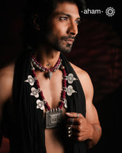 This Tribal Silver Neckpiece artfully combines vintage and contemporary elements. At its heart lies a vintage Ganesh Lakshmi pendant, surrounded by newly crafted paan-shaped beads inspired by traditional designs. Crafted in silver, the piece is elevated by rich maroon Powai accents that add a dramatic and elegant touch, making it a unique statement of timeless artistry.This Tribal Silver Neckpiece artfully combines vintage and contemporary elements. At its heart lies a vintage Ganesh Lakshmi pendant, surrou