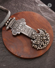 This Tribal Silver Neckpiece showcases a unique vintage buckle pendant sourced from the Rajasthan/Gujarat region, paired with a cluster of traditional ghungroos. The hand-woven silver chain adds intricate craftsmanship, making this statement piece a remarkable blend of heritage and artistry. Perfect for those who appreciate authentic, handcrafted silver jewellery with cultural significance.