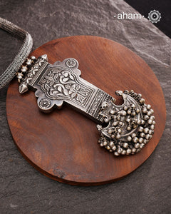 This Tribal Silver Neckpiece showcases a unique vintage buckle pendant sourced from the Rajasthan/Gujarat region, paired with a cluster of traditional ghungroos. The hand-woven silver chain adds intricate craftsmanship, making this statement piece a remarkable blend of heritage and artistry. Perfect for those who appreciate authentic, handcrafted silver jewellery with cultural significance.