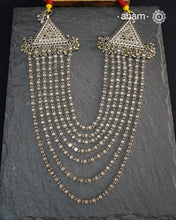 This Tribal Multi Line Silver Neckpiece is a magnificent classic Rani haar featuring seven intricately crafted lines, known as Satlada. It is adorned with a delicate floral pattern and accented by two prominent triangular motifs at each end. This vintage design exudes timeless elegance and cultural richness, making it a treasured heirloom piece meant to be passed down through generations. A neckpiece truly fit for a queen.