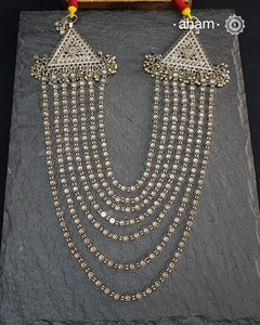 This Tribal Multi Line Silver Neckpiece is a magnificent classic Rani haar featuring seven intricately crafted lines, known as Satlada. It is adorned with a delicate floral pattern and accented by two prominent triangular motifs at each end. This vintage design exudes timeless elegance and cultural richness, making it a treasured heirloom piece meant to be passed down through generations. A neckpiece truly fit for a queen.