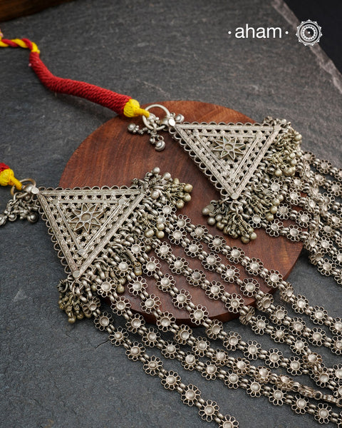 This Tribal Multi Line Silver Neckpiece is a magnificent classic Rani haar featuring seven intricately crafted lines, known as Satlada. It is adorned with a delicate floral pattern and accented by two prominent triangular motifs at each end. This vintage design exudes timeless elegance and cultural richness, making it a treasured heirloom piece meant to be passed down through generations. A neckpiece truly fit for a queen.