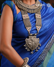 For those seeking a bold and striking accessory, the Shrenathji Tribal Silver Neckpiece is an exceptional choice. It features a large Shrinathji pendant, meticulously recreated from a vintage museum piece, complemented by side neckpiece bands characteristic of Jaisalmer craftsmanship. This piece is designed for women who appreciate distinctive, statement-making jewellery rooted in rich cultural heritage.