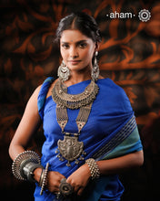 For those seeking a bold and striking accessory, the Shrenathji Tribal Silver Neckpiece is an exceptional choice. It features a large Shrinathji pendant, meticulously recreated from a vintage museum piece, complemented by side neckpiece bands characteristic of Jaisalmer craftsmanship. This piece is designed for women who appreciate distinctive, statement-making jewellery rooted in rich cultural heritage.
