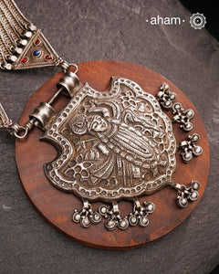 For those seeking a bold and striking accessory, the Shrenathji Tribal Silver Neckpiece is an exceptional choice. It features a large Shrinathji pendant, meticulously recreated from a vintage museum piece, complemented by side neckpiece bands characteristic of Jaisalmer craftsmanship. This piece is designed for women who appreciate distinctive, statement-making jewellery rooted in rich cultural heritage.