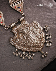For those seeking a bold and striking accessory, the Shrenathji Tribal Silver Neckpiece is an exceptional choice. It features a large Shrinathji pendant, meticulously recreated from a vintage museum piece, complemented by side neckpiece bands characteristic of Jaisalmer craftsmanship. This piece is designed for women who appreciate distinctive, statement-making jewellery rooted in rich cultural heritage.