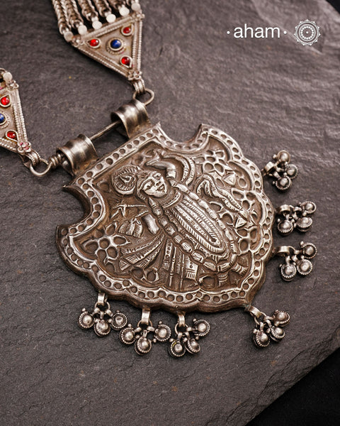 For those seeking a bold and striking accessory, the Shrenathji Tribal Silver Neckpiece is an exceptional choice. It features a large Shrinathji pendant, meticulously recreated from a vintage museum piece, complemented by side neckpiece bands characteristic of Jaisalmer craftsmanship. This piece is designed for women who appreciate distinctive, statement-making jewellery rooted in rich cultural heritage.