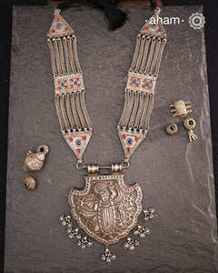 For those seeking a bold and striking accessory, the Shrenathji Tribal Silver Neckpiece is an exceptional choice. It features a large Shrinathji pendant, meticulously recreated from a vintage museum piece, complemented by side neckpiece bands characteristic of Jaisalmer craftsmanship. This piece is designed for women who appreciate distinctive, statement-making jewellery rooted in rich cultural heritage.