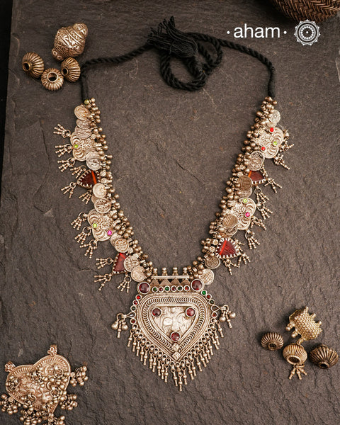 This Tribal Silver Neckpiece features a stunning pendant as the central piece and multiple small amulets and glass beads along with multiple ghungroos for added drama. A true treasure for any jewellery lover.