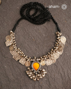This Tribal Silver Neckpiece features a stunning glass pendant as the central piece and multiple small amulets and glass beads along with multiple ghungroos for added drama. A true treasure for any jewellery lover.
