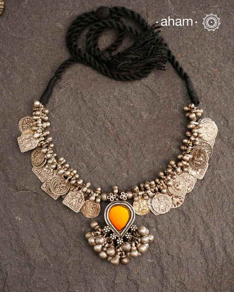 This Tribal Silver Neckpiece features a stunning glass pendant as the central piece and multiple small amulets and glass beads along with multiple ghungroos for added drama. A true treasure for any jewellery lover.