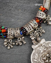 This Tribal Silver Neckpiece features a stunning pendant as the central piece and multiple small amulets and glass beads along with multiple ghungroos for added drama. A true treasure for any jewellery lover.