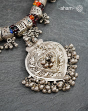 This Tribal Silver Neckpiece features a stunning pendant as the central piece and multiple small amulets and glass beads along with multiple ghungroos for added drama. A true treasure for any jewellery lover.