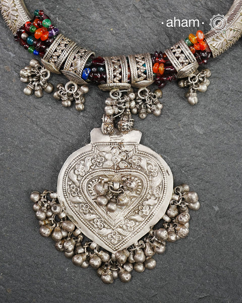 This Tribal Silver Neckpiece features a stunning pendant as the central piece and multiple small amulets and glass beads along with multiple ghungroos for added drama. A true treasure for any jewellery lover.