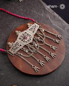 This Tribal Silver Choker features a unique design, with a silver armband transformed into a stylish choker. Adorned with beautiful chilai work and colorful stone accents, this piece adds a touch of cultural elegance to any outfit. Enhance your style with this one-of-a-kind choker.