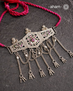 This Tribal Silver Choker features a unique design, with a silver armband transformed into a stylish choker. Adorned with beautiful chilai work and colorful stone accents, this piece adds a touch of cultural elegance to any outfit. Enhance your style with this one-of-a-kind choker.