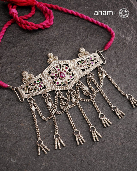 This Tribal Silver Choker features a unique design, with a silver armband transformed into a stylish choker. Adorned with beautiful chilai work and colorful stone accents, this piece adds a touch of cultural elegance to any outfit. Enhance your style with this one-of-a-kind choker.