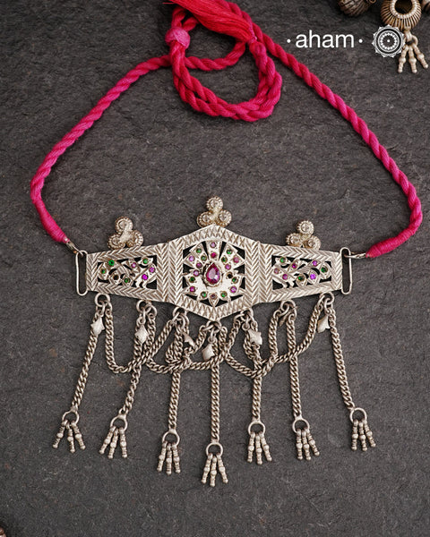This Tribal Silver Choker features a unique design, with a silver armband transformed into a stylish choker. Adorned with beautiful chilai work and colorful stone accents, this piece adds a touch of cultural elegance to any outfit. Enhance your style with this one-of-a-kind choker.