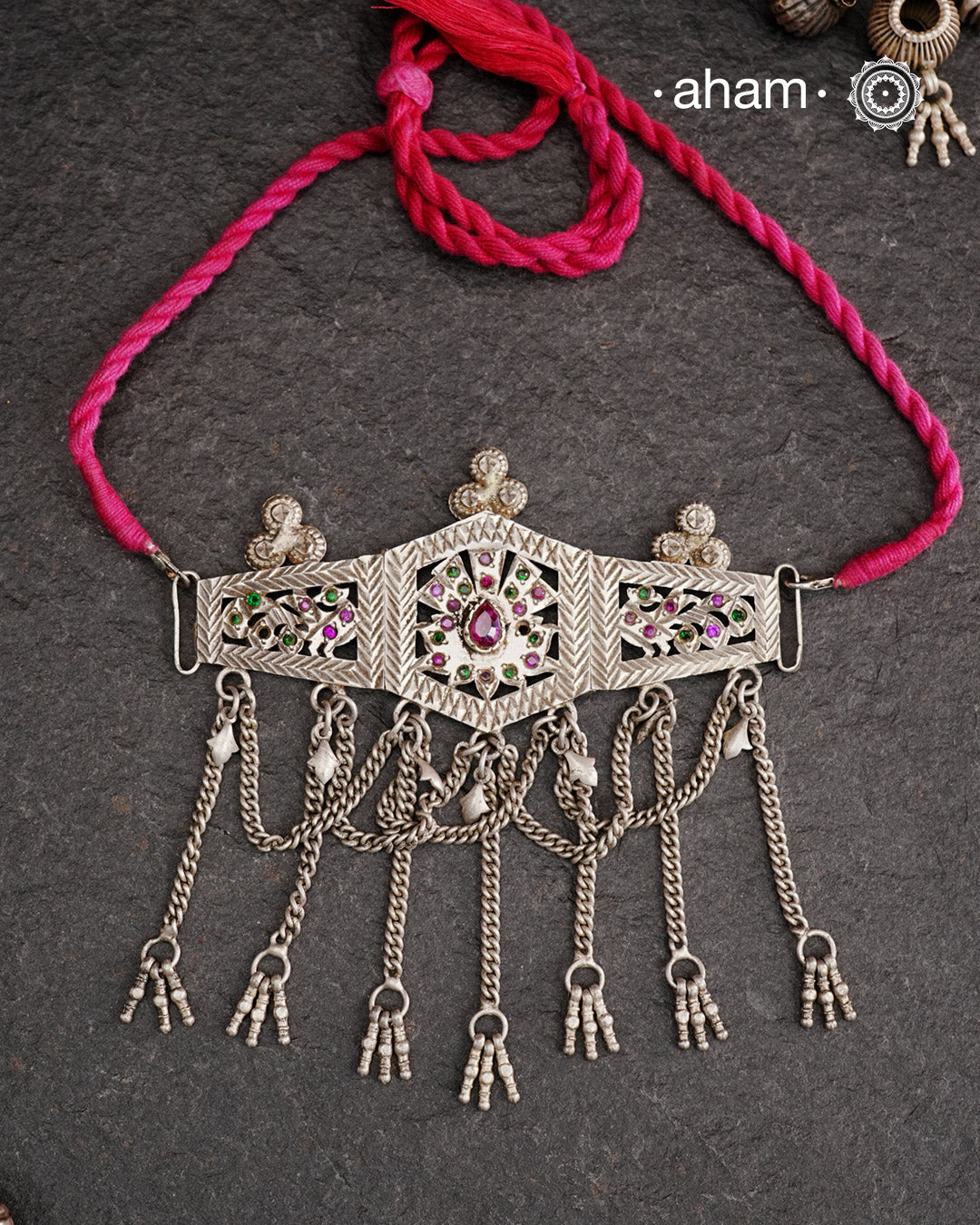 This Tribal Silver Choker features a unique design, with a silver armband transformed into a stylish choker. Adorned with beautiful chilai work and colorful stone accents, this piece adds a touch of cultural elegance to any outfit. Enhance your style with this one-of-a-kind choker.